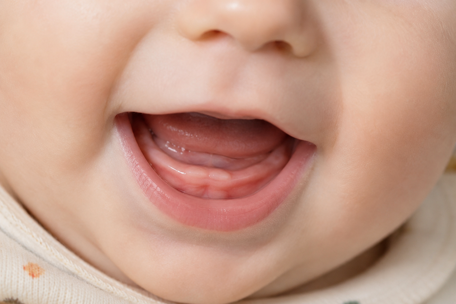 Bebé sonriendo con sus primeros dientes asomando en la encía